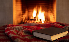 Book On A Blanket, Fireplace Burning Firewood Background. Reading And Relax Near The Fire