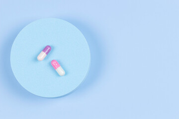 Round geometric shape platform podium with colorful medicine pills capsules on light blue background. Top view, flat lay, copy space for text