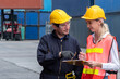 © InfiniteFlow - Industrial worker works with co-worker at overseas shipping container yard . Logistics supply chain management and international goods export concept .