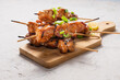 Chicken fillet yakitori on a white table. Appetizing slices of fried chicken on skewers.