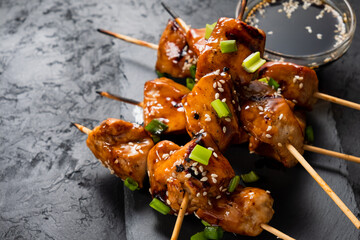 Sticker - Chicken skewers sprinkled with onions and sesame seeds close-up in an Asian style in a sweet sauce.