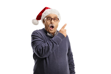 Wall Mural - Surprised mature man with a santa claus hat pointing