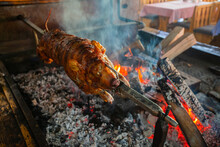 Delicious Spit Roasted Suclinkg Pig , Grilled Using Hot Charcoal. Fire Place In The Restaurant.