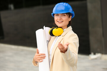 Poster - Female industrial engineer in hardhat with plans of house outdoors