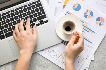 Fototapete - Woman working with laptop, cup of coffee and charts on light background