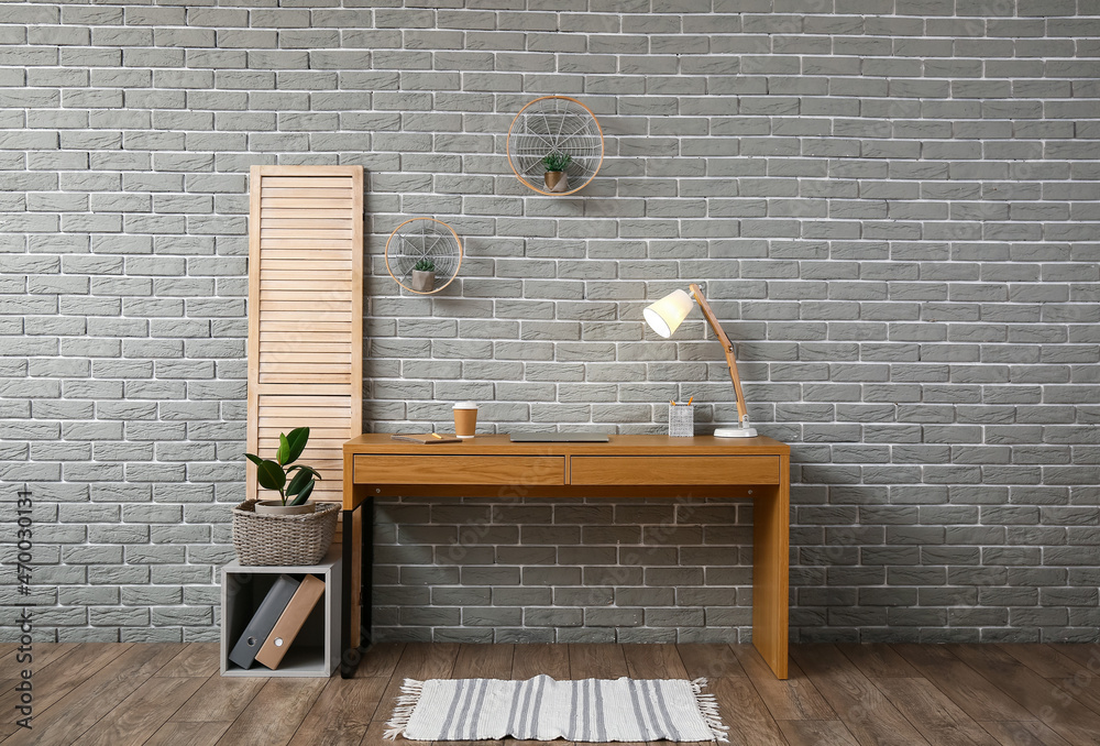 Comfortable workplace near brick wall in interior of room