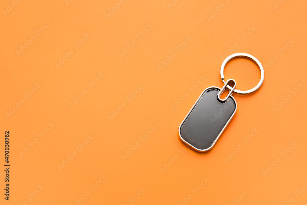 Stylish metallic keychain on orange background