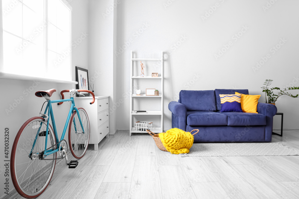 Stylish interior with bicycle and blue sofa in room