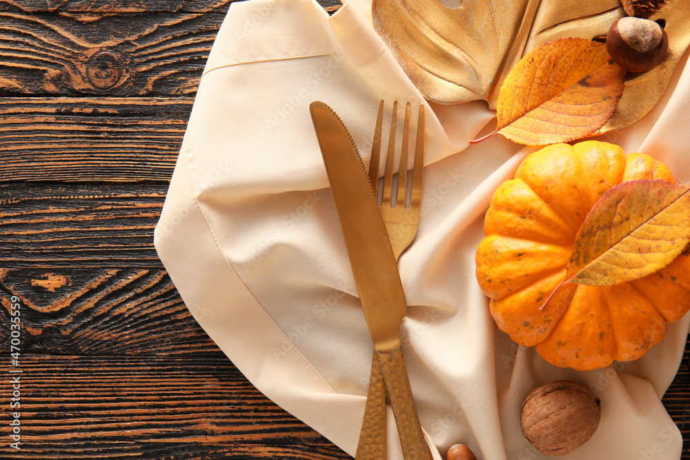 Composition with table setting, pumpkin and autumn leaves on wooden background