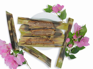 Wall Mural - Top view of Thai traditional sweet food Kanom Jak (Coconut Sweet Rice Flour Thai Dessert) in white plate decorated with pink magenta bougainvillea paper flowers isolated on white background.