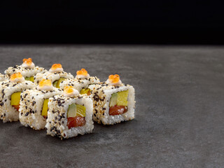 Wall Mural - Salmon, avocado, egg omelette wrapped in rice. Served with red salmon caviar and sesame seeds. Japanese traditional sushi roll dish on concrete background. Single object. Copy space image
