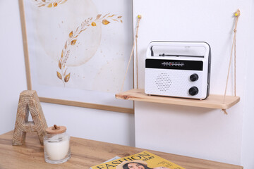 Wooden shelf with stylish radio on white wall indoors