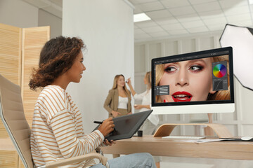 Fototapete - Professional African American retoucher working with graphic tablet at desk in photo studio