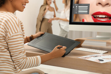 Fototapete - Professional retoucher working with graphic tablet at desk in photo studio, closeup
