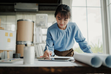 Selective focus, Asian female architect or engineer Drawing the design of the building's interior using a tablet. Asian female architect or engineer Sit and analyze, design projects in the office.