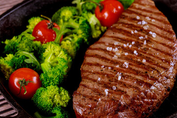 Wall Mural - Grilled medium rare beef chop with sea salt, broccoli and tomato on grill pan.