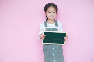 Wall Mural - Portrait beautiful cute asian child girl on pink background with drawing board holding in hand