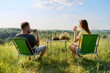 Happy middle-aged married couple having rest outdoors, in meadow, back view.