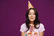 © Drobot Dean - White brunette woman blowing candle on birthday cake