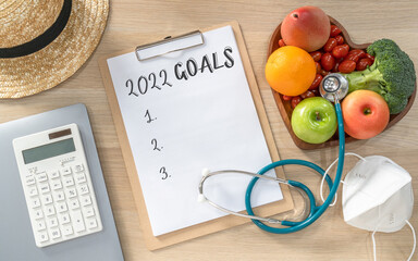 2022 New Year Goals in new normal lifestyle, work-life balance with face mask safety from covid-19, healthy  cholesterol diet food, good heart health on blank resolution list on paper medical notepad