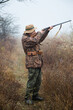 © AlexR - hunter man with a gray beard in hunter suit makes aiming wiring with a double-barreled rifle