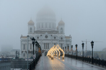 Wall Mural - View of the white Cathedral of Christ the Saviour and the bridge with Christmas decorations on a cloudy winter. Misty winter morning in Moscow