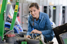 Young Female Farmer Fixing A Tractor