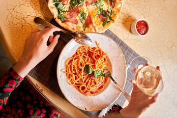 Wall Mural - Woman eats Italian pasta with tomato, meat. Close-up spaghetti Bolognese wind it around a fork with a spoon. Parmesan cheese