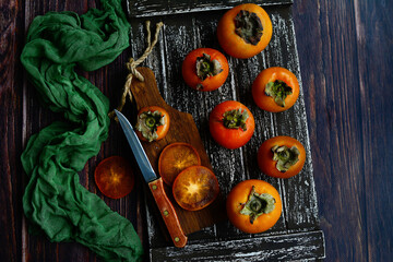 Wall Mural - Juicy ripe persimmon on a dark wooden background. View from above.