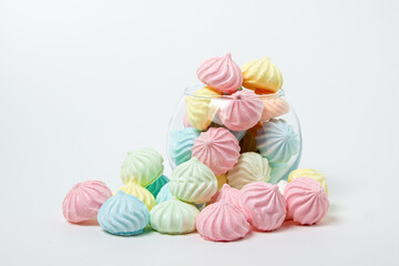 Sticker - Multicolored meringues on a white background. Glass vase overflowing with multicolored meringues.