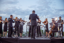 Orchestra Playing Classic Instrumental Music Under Cloudy Sky