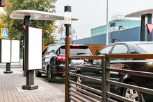 Customers Waiting In Their Cars Line Up At The Drive Thru Facility Of A Fast Food Restaurant. Empty Blank Vertical Banners Installed Near Drive-thru Window. Mockup. Mock-up. Poster
