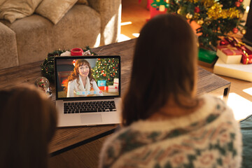 Canvas Print - Mother and daughter making laptop christmas video call with smiling caucasian woman