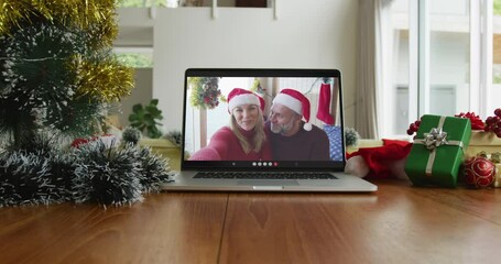 Canvas Print - Smiling caucasian couple wearing santa hats on christmas video call on laptop