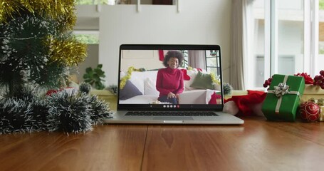 Wall Mural - Smiling african american woman wearing santa hat on christmas video call on laptop