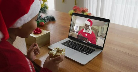 Poster - African american woman with santa hat using laptop for christmas video call with santa on screen