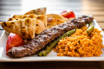 Traditional Turkish Adana kebab or kebap meat food with marinated peppers,  bread and rice pilaf. Top view