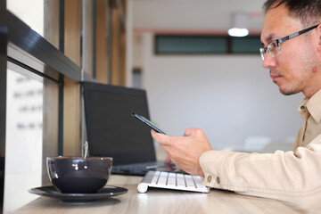 Poster - Concept of unrecognisable businessman using a laptop while working remotely, hands working on modern laptop. Office desktop and using smartphone 