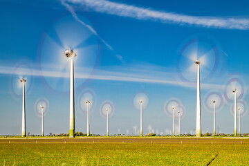 rotating wind turbines of a wind park with condensation trails crossing the sky-2601