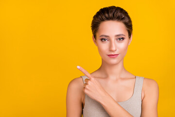 Wall Mural - Portrait of attractive shine girl demonstrating copy empty blank space isolated over bright yellow color background