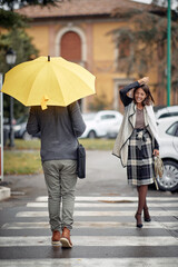 Wall Mural - Some handsome and elegant young woman and man pass each other at a pedestrian crossing on a rainy day. Walk, rain, city