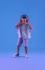 Wall Mural - Cute dancing African-American boy with headphones on color background