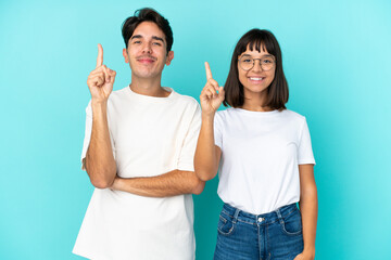 Young mixed race couple isolated on blue background showing and lifting a finger in sign of the best