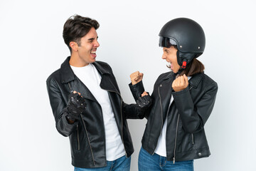 Young mixed race couple with a motorcycle helmet isolated on white background celebrating a victory in winner position