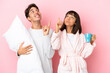 © luismolinero - Young couple in pajamas isolated on pink background pointing with the index finger a great idea