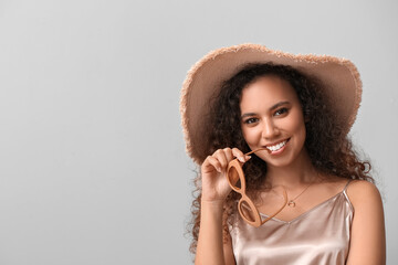 Wall Mural - Beautiful African-American woman in broad brim hat on light background