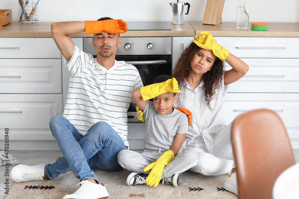 Tired interracial family resting after cleaning kitchen