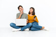 © luismolinero - Young couple with a laptop and mobile sitting on the floor thinking an idea while looking up
