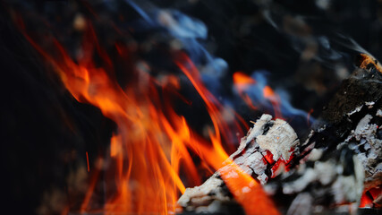 Bonfire flame with coals. Burning wood with embers. Fire with smoke and sparks. Close-up with copy space.