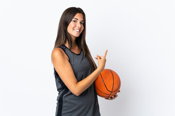 Wall Mural - Young brazilian woman playing basketball isolated on white background pointing finger to the side